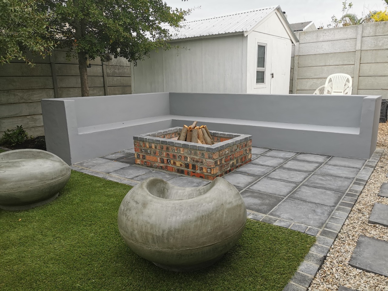 A modern outdoor kitchen with built-in braai, sink, and counter space.